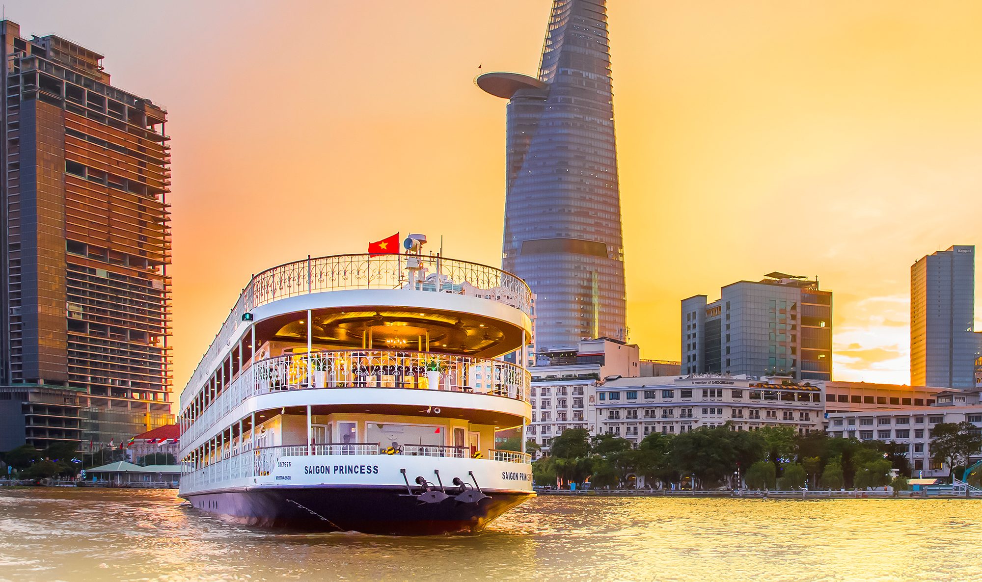 Du thuyền Saigon Princess trên sông Sài Gòn lúc hoàng hôn với hậu cảnh là các tòa nhà cao tầng và tháp Bitexco.