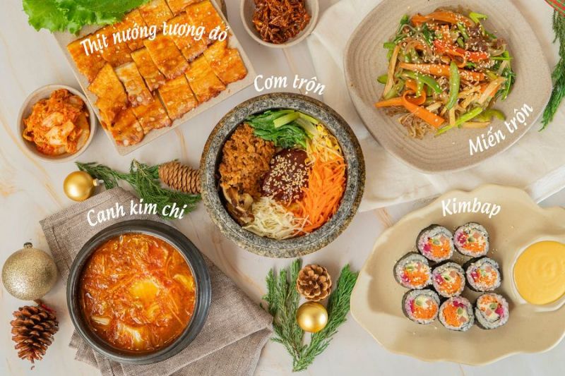 Bàn ăn Hàn Quốc với các món truyền thống gồm cơm trộn, canh kim chi, miến trộn, kimbap và thịt nướng sốt tương đỏ – được phục vụ tại nhà hàng Busan Korean Food mang phong cách chuẩn Hàn.