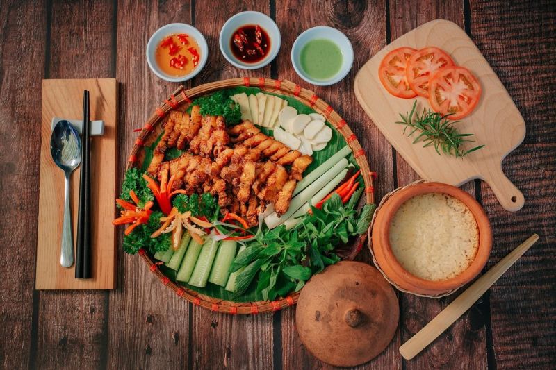 Phần cơm niêu tại Cơm Niêu Việt Nam gồm cơm cháy giòn cạnh niêu đất, món ăn kèm phong vị ba miền, phục vụ trong không gian gần gũi với nhân viên mặc áo bà ba truyền thống.