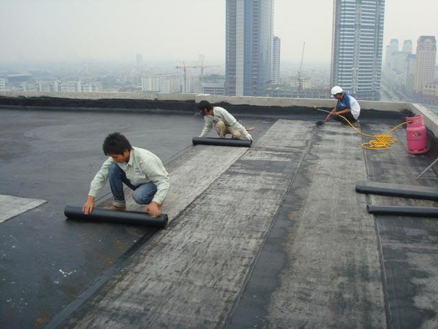 Nhân viên công ty Gia Định đang thi công lớp chống thấm nhà ở trên mái cao tầng bằng phương pháp màng bitum nóng chảy tại TP.HCM.