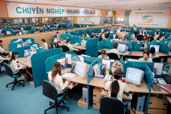 Trung tâm chăm sóc khách hàng Viettel với nhiều nhân viên đang làm việc tại các bàn máy tính, môi trường chuyên nghiệp với khẩu hiệu “Chuyên nghiệp – Nhanh – Hiệu quả” treo trên tường.