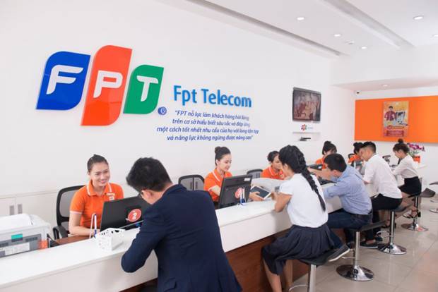 Trung tâm giao dịch FPT Telecom – công ty công nghệ thông tin – viễn thông hàng đầu Việt Nam, với nhiều nhân viên mặc đồng phục cam đang hỗ trợ khách hàng tại quầy trong môi trường chuyên nghiệp và hiện đại.