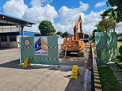 Cảnh thi công công trình hạ tầng kỹ thuật của Công Ty Cải Tạo Nhà Gia Cát tại TP.HCM với xe xúc, biển báo an toàn và hàng rào bảo hộ.