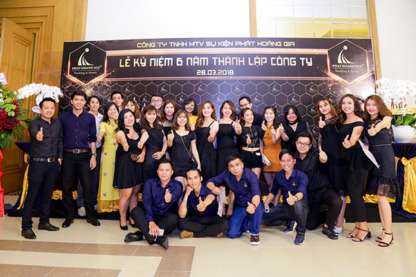 Tập thể nhân sự công ty tổ chức lễ kỷ niệm Phát Hoàng Gia tạo dáng trước backdrop mừng 6 năm thành lập, trong không gian sự kiện chuyên nghiệp và hiện đại.