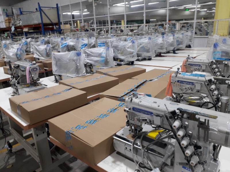 Hàng dài máy may công nghiệp Kingtex mới lắp, phủ nilon, kèm thùng carton tại xưởng lắp ráp và cung cấp may móc Tân Thành.