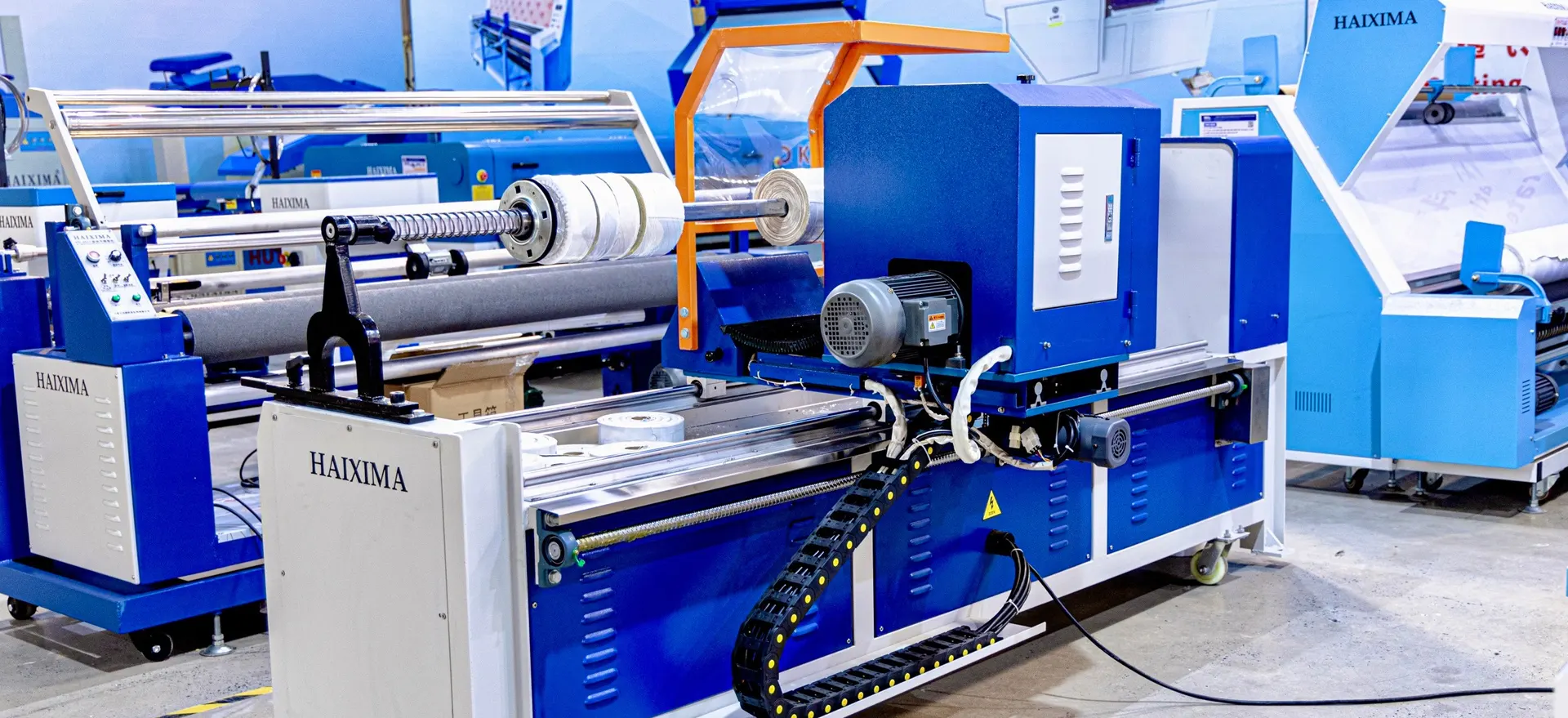 Máy cắt – quấn vải HAIXIMA màu xanh, hệ thống tự động hóa hiện đại trong xưởng may công nghiệp tại TP.HCM.