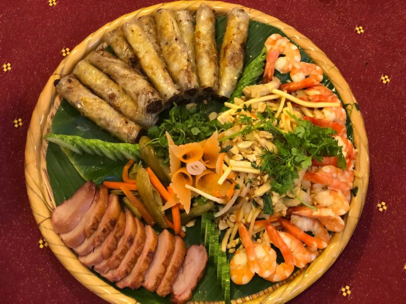 Mâm đặc sản núi rừng Tây Bắc gồm chả ram, gỏi tôm xoài, thịt lợn hun khói và rau rừng bày trí trên mẹt tre lá chuối tại nhà hàng Ẩm Thực Quê Nhà.