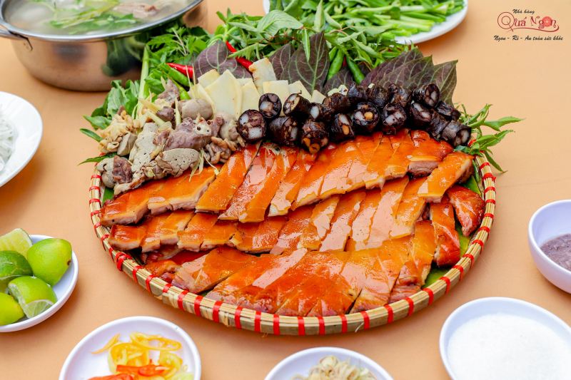 Mâm đặc sản núi rừng tại Nhà Hàng Quá Ngon gồm thịt heo tộc quay giòn, rau rừng, mắm nêm, các món ăn kèm như lòng heo, măng, cà niễng và chẩm chéo, được bày biện đẹp mắt trên mẹt tre.