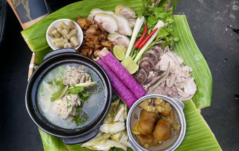 Mâm đặc sản núi rừng Tây Bắc tại Bếp Vùng Cao By Sơn gồm thịt gà luộc, gà nướng, dồi, lòng, măng chua, canh xương, chân giò hầm và rau rừng, tất cả được bày trên lá chuối mang đậm phong vị bản địa.