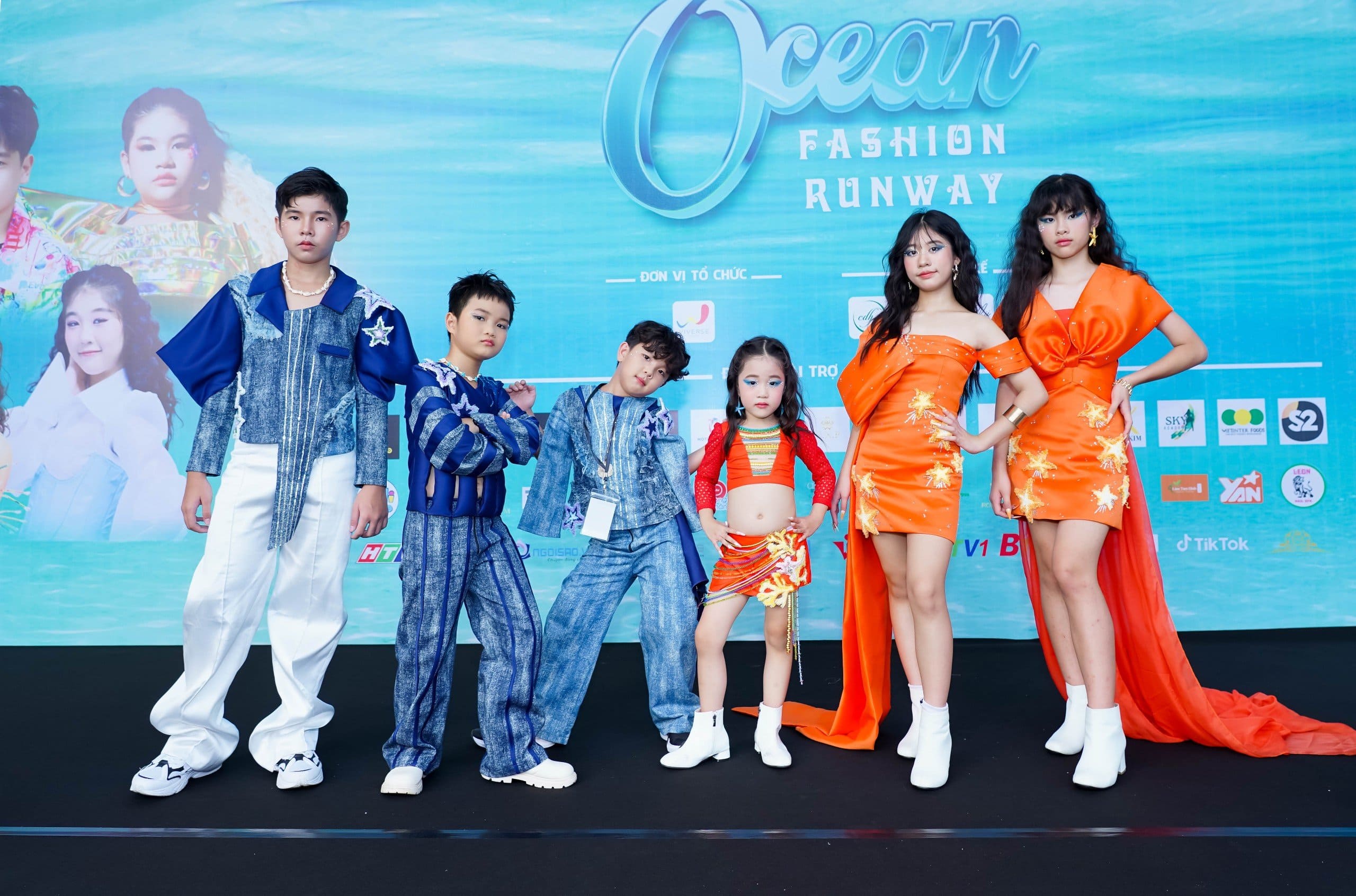 Sáu mẫu nhí và tuổi teen tạo dáng trên sân khấu “Ocean Fashion Runway”, trang phục denim xanh và cam rực rỡ.