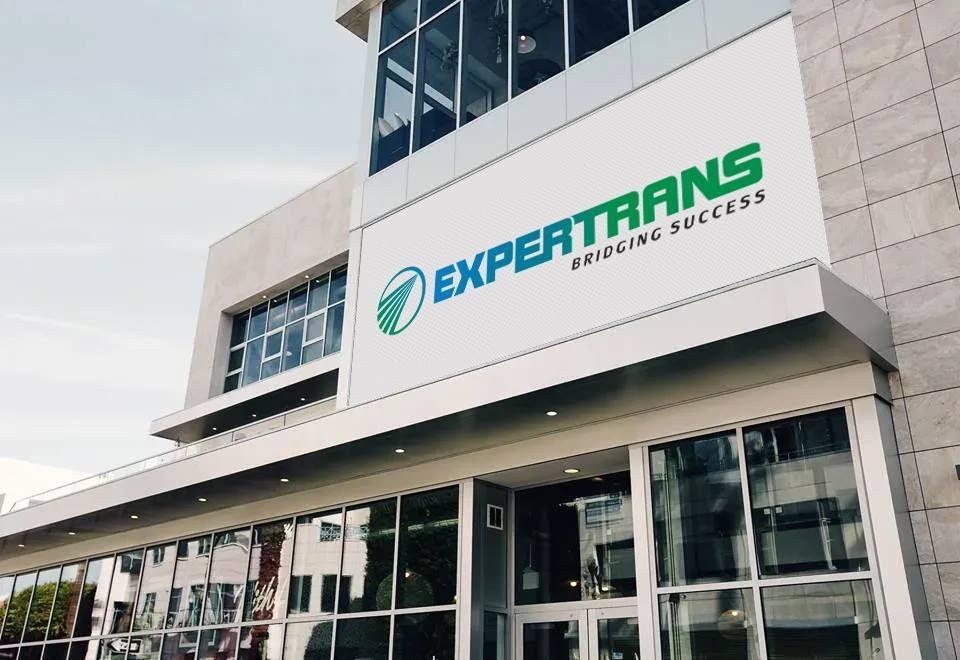 Tòa nhà văn phòng hiện đại với biển hiệu Expertrans và khẩu hiệu “Bridging Success”, đại diện cho công ty dịch thuật quốc tế chuyên tiếng Trung và hơn 100 ngôn ngữ khác.
