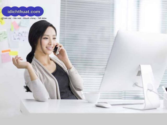 Người phụ nữ đang làm việc tại văn phòng với máy tính và điện thoại, biểu trưng cho dịch vụ dịch thuật tiếng Trung chuyên nghiệp, nhanh chóng và hỗ trợ trực tuyến từ idichthuat.com.