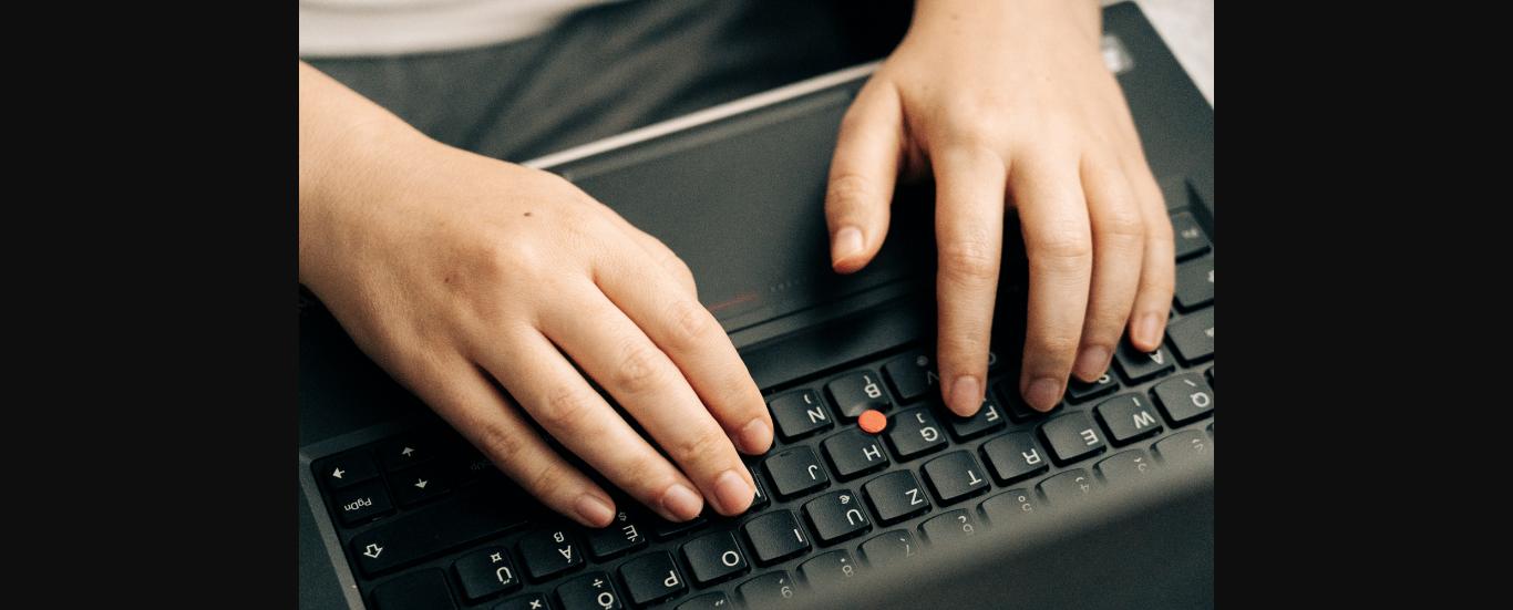 Đôi tay gõ bàn phím laptop khi làm bài tập về nhà