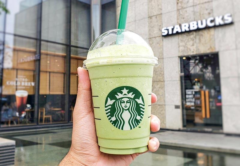 Một tay cầm ly matcha ngon Frappuccino trước cửa hàng Starbucks tại TP.HCM.