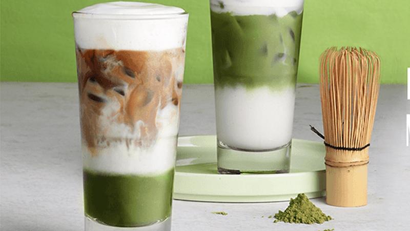 Ly Matcha Macchiato tại Phê La với lớp foam sữa mặn nổi bật, đặt trên bàn gỗ trong không gian quán xanh mát và tối giản.