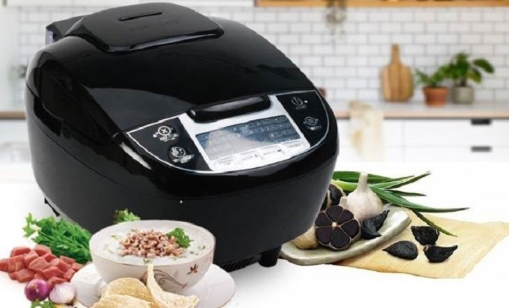 Máy làm tỏi đen đa năng màu đen bóng hiện đại bên cạnh đĩa tỏi đen thành phẩm và bát cháo dinh dưỡng trong không gian bếp.