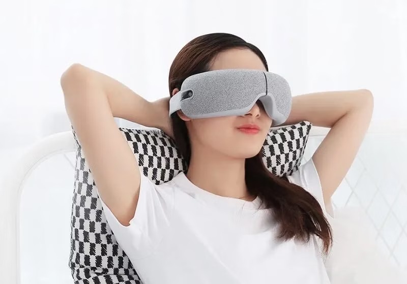 Cô gái thư giãn với máy massage mắt.