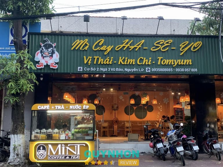 Mặt tiền quán mì cay Ha-se-yo với bảng hiệu xanh, đèn vàng và không gian bên trong ấm cúng tại TP.HCM.