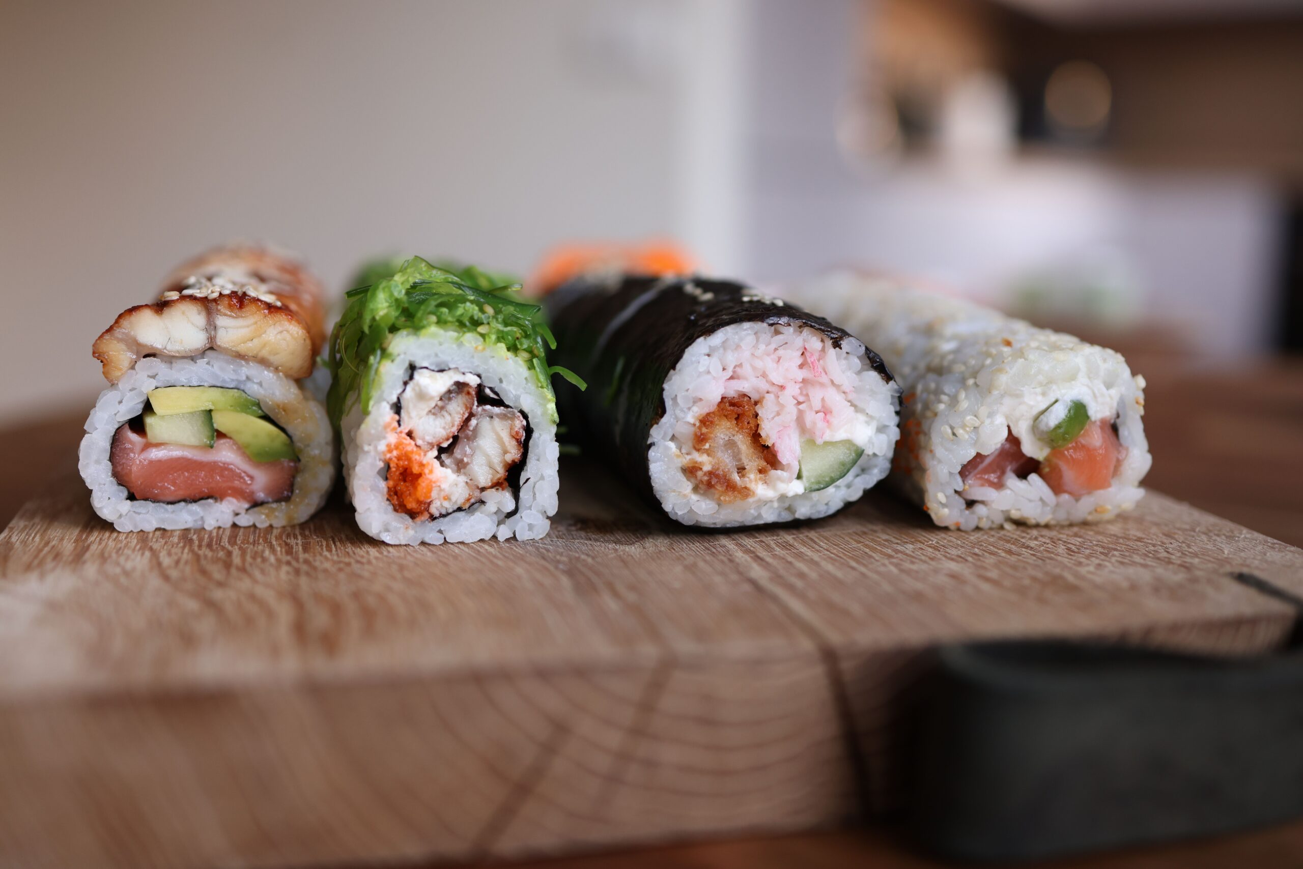 bốn cuộn sushi maki tươi ngon trên thớt gỗ