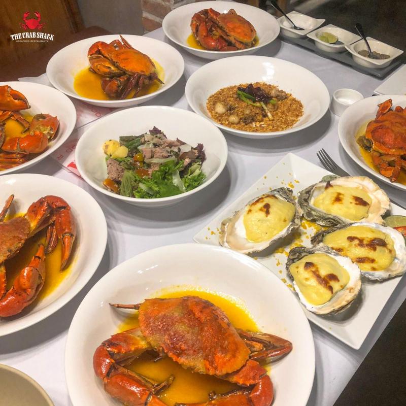 Bàn ăn đầy ắp món cua luộc sốt bơ kiểu Mỹ, hàu đút lò phô mai và salad tại The Crab Shack – quán cua phong cách Louisiana nổi bật tại TP.HCM.
