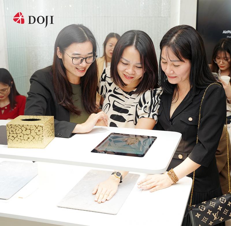 Ba nữ khách hàng đang được tư vấn trang sức tại showroom DOJI với thiết bị trình chiếu hiện đại, thể hiện sự chuyên nghiệp và trải nghiệm cao cấp của thương hiệu trang sức.