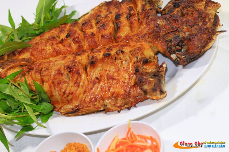 Cận cảnh món cá nướng thơm lừng, da giòn vàng ươm, ăn kèm rau sống và nước chấm, được phục vụ tại nhà hàng Hải Sản Giang Ghẹ – địa điểm tổ chức liên hoan nổi bật tại TP.HCM.


