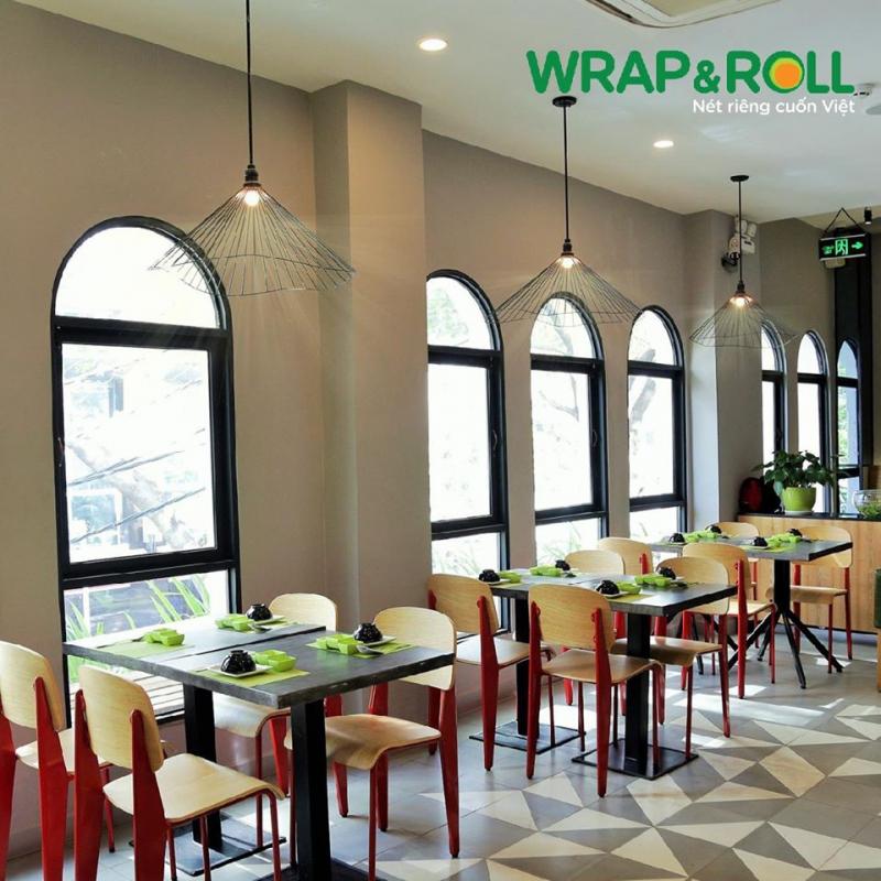 Không gian nhà hàng Wrap & Roll với nội thất hiện đại, tông màu sáng, bàn ăn được sắp xếp gọn gàng – phù hợp cho các buổi liên hoan cuối năm phong cách trẻ trung và tinh tế.