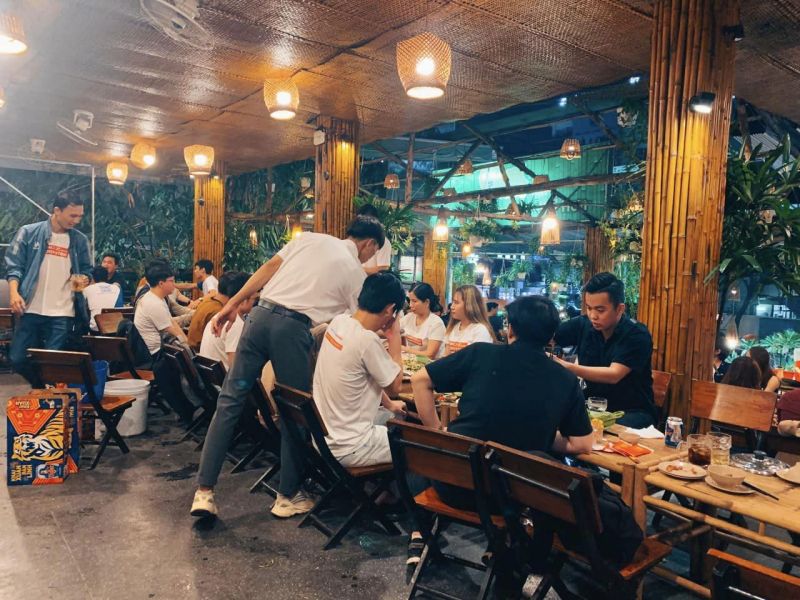 Nhóm nhân viên công sở tụ họp tại quán 437 với không gian bàn ghế gỗ, trang trí tre nứa, ăn uống trong không khí thân thiện, ấm cúng.