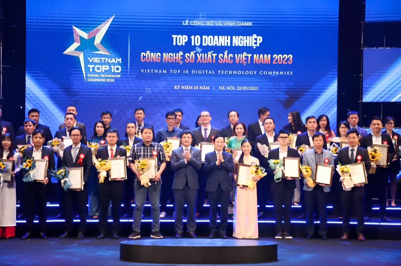 “Sân khấu lễ vinh danh Vietnam Top 10 Digital Technology Companies 2023 với hàng chục lãnh đạo cầm hoa và bằng khen; đại diện GMO-Z.com đứng hàng đầu, thể hiện thành tích đổi mới công nghệ.”