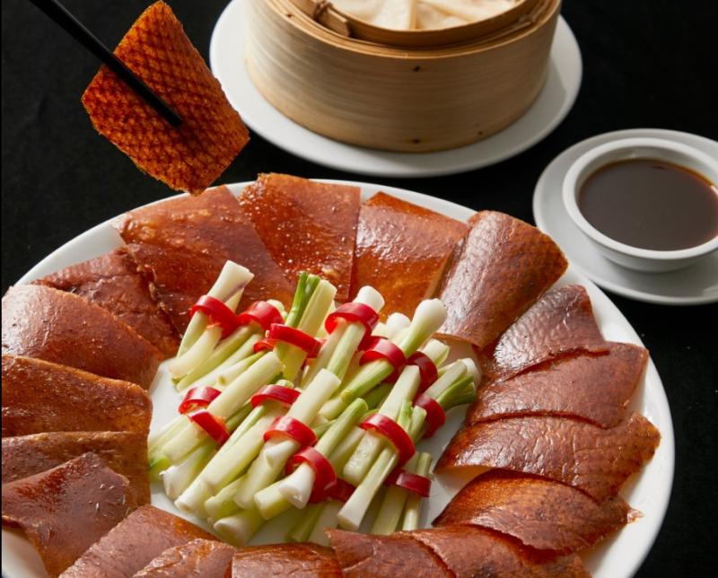Đĩa vịt quay cắt lát mỏng với lớp da giòn đều màu hổ phách, ăn kèm hành lá cuốn ớt, bánh tráng hấp và chén nước sốt đậm vị tại nhà hàng Tân Hải Vân.