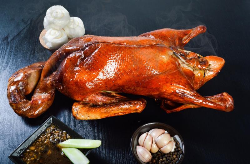 Nguyên con vịt quay Trần Quang Ký với lớp da cánh gián bóng giòn, bày trên bàn cùng nước sốt đặc chế, tỏi và gia vị truyền thống.